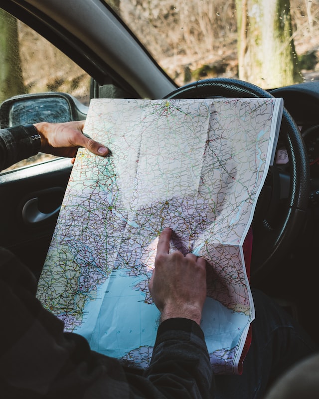 A driver planning a route with a map inside the car